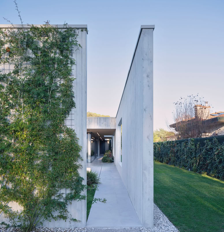 Vista dell'ingresso della villa a San Donà di Piave progettata da MIDE architetti immersa nel verde e disegnata con geometrie pulite che regalano privacy all'abitazione.