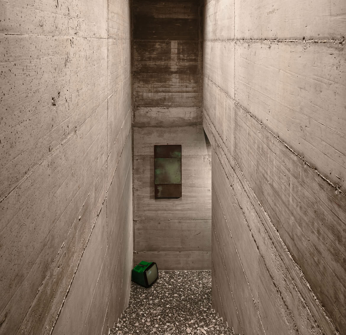 Una scala monumentale in terrazzo con pareti lasciate con il calcestruzzo a vista che donano un carattere brutalista a questa casa progettata da MIDE architetti.