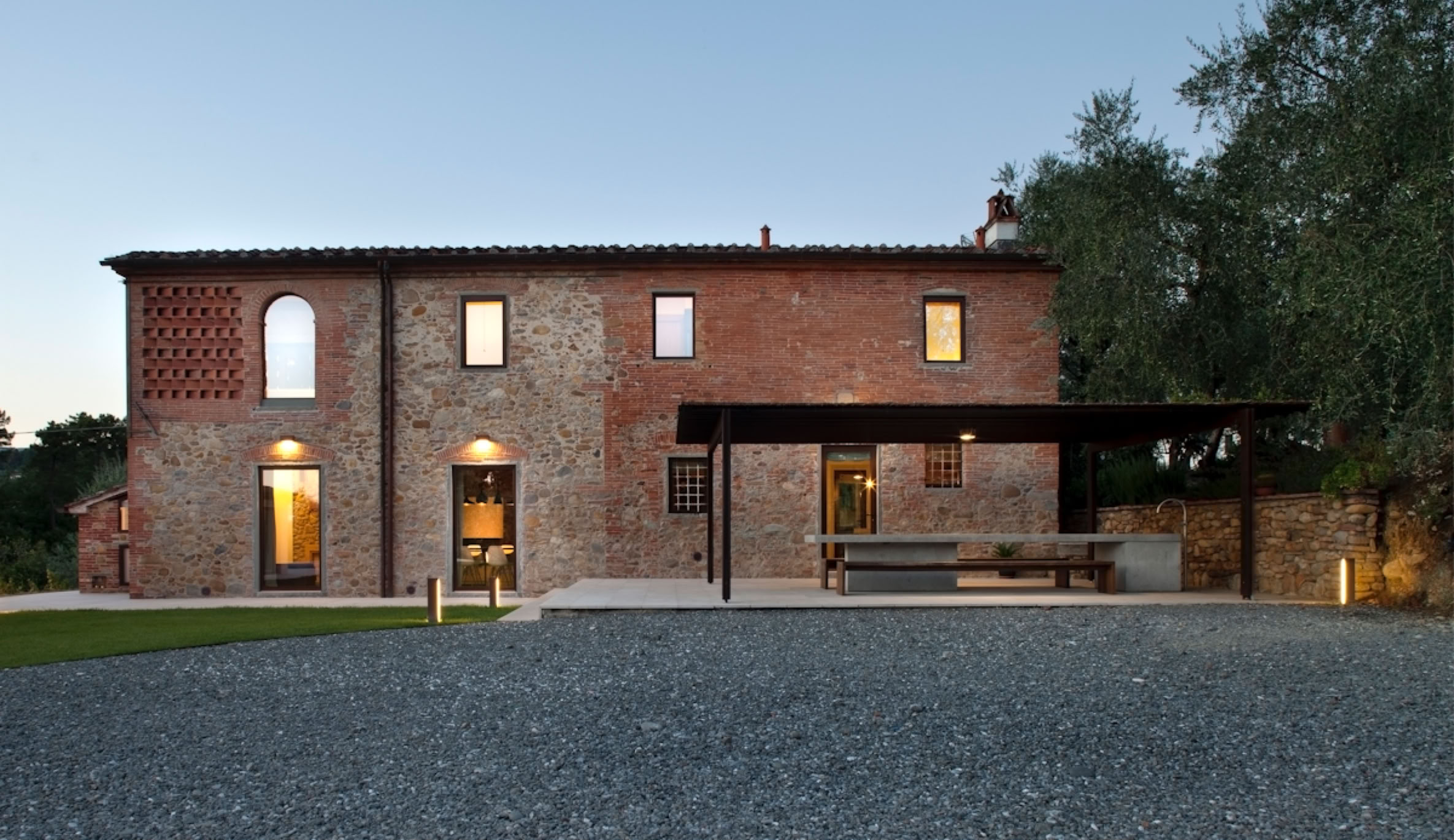 Stone and exposed brick façade with steel-framed windows and wooden shutters, enhancing the character of traditional Tuscan architecture.