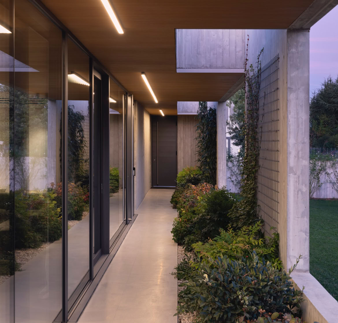 Vista del portico esterno della villa a San Donà di Piave progettata da MIDE architetti immersa nel verde e disegnata con geometrie pulite che regalano privacy all'abitazione.