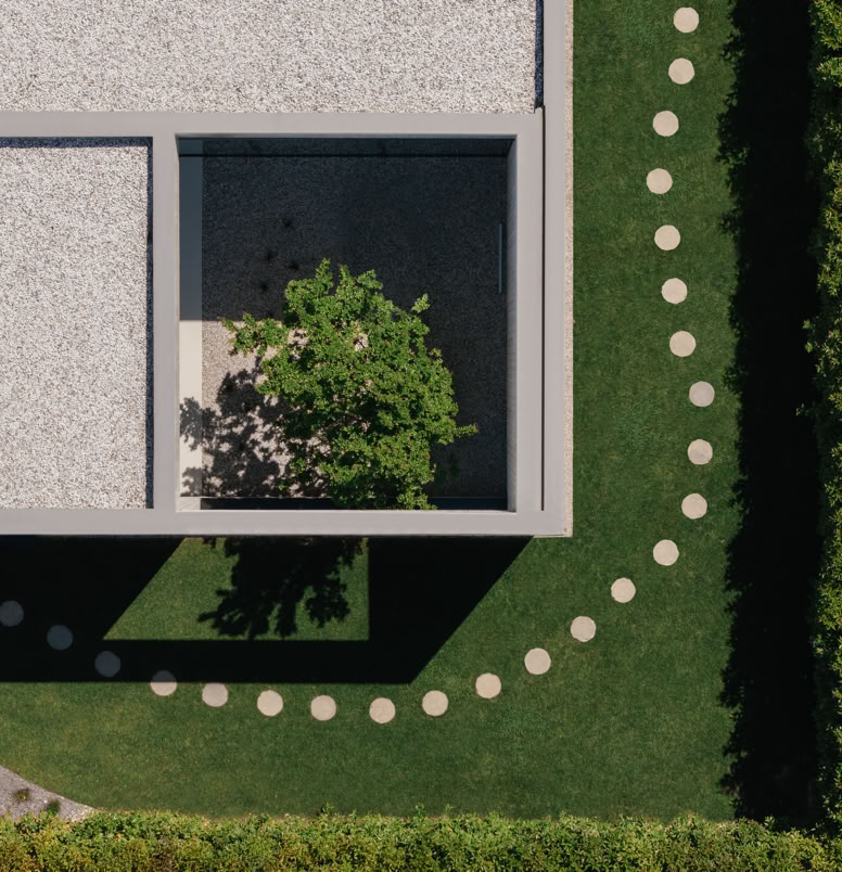 Corte centrale della villa progettata da MIDE architetti, dove il calcestruzzo a vista dialoga con la vegetazione, creando un’atmosfera sospesa tra interno ed esterno.