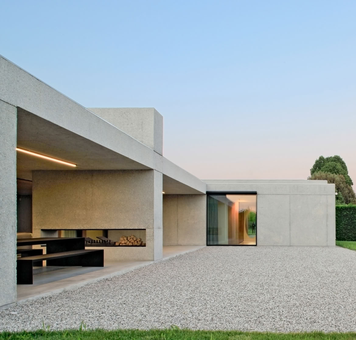 Villa unifamiliare su un unico piano progettata da MIDE architetti, con volumi essenziali in calcestruzzo sabbiato e ampie vetrate rivolte al giardino.