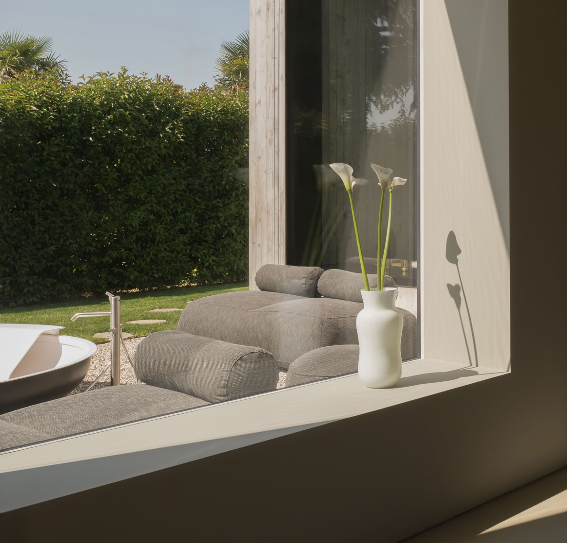 Zona relax e studio progettata con ampie vetrate per godere del giardino che circonda la casa progettata da MIDE architetti.