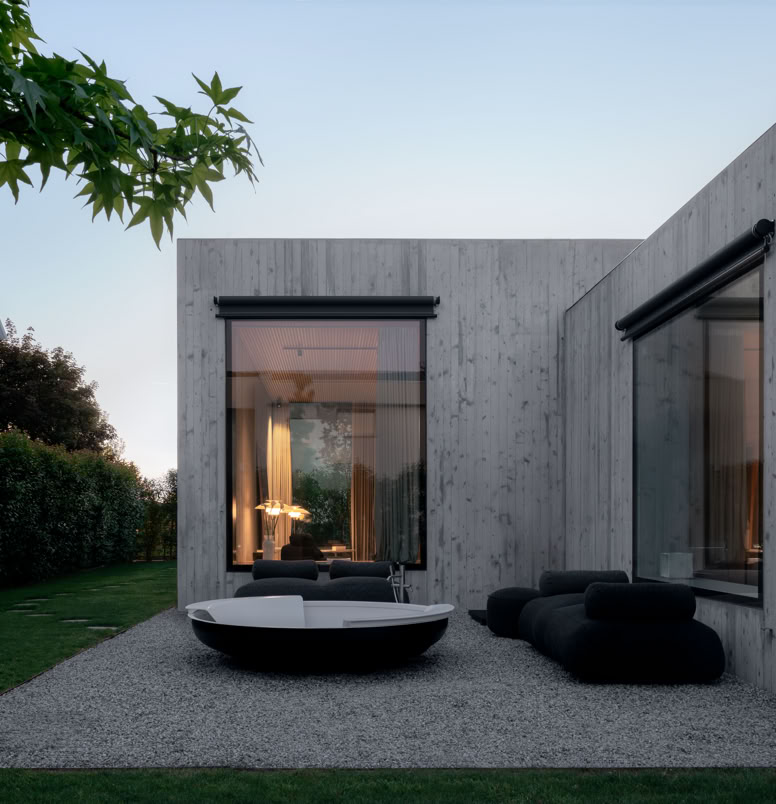 Piscina di design incastonata tra due volumi della villa, sul retro, come spazio privato e raccolto. L’acqua riflette le superfici in calcestruzzo e la vegetazione circostante, amplificando la sensazione di calma e continuità tra architettura e natura.