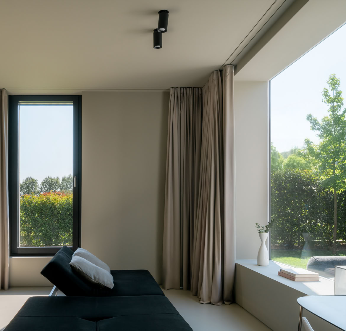 Zona relax e studio progettata con ampie vetrate per godere del giardino che circonda la casa progettata da MIDE architetti.