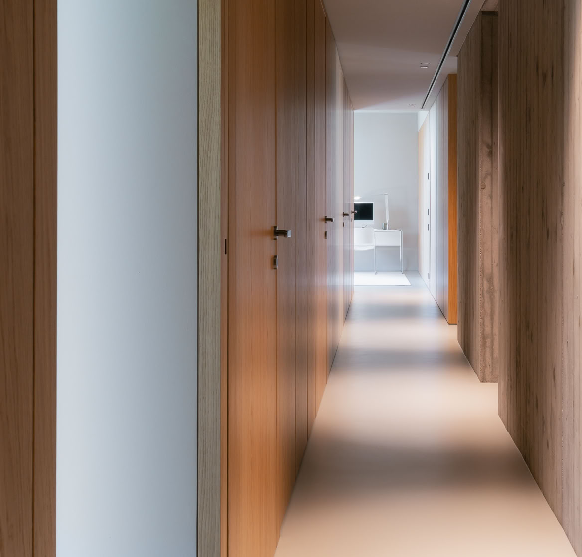 Contemporary interiors for the sleeping area of this villa designed by MIDE architetti, featuring custom built-in wooden wardrobes that enhance the warmth and refinement of the space.