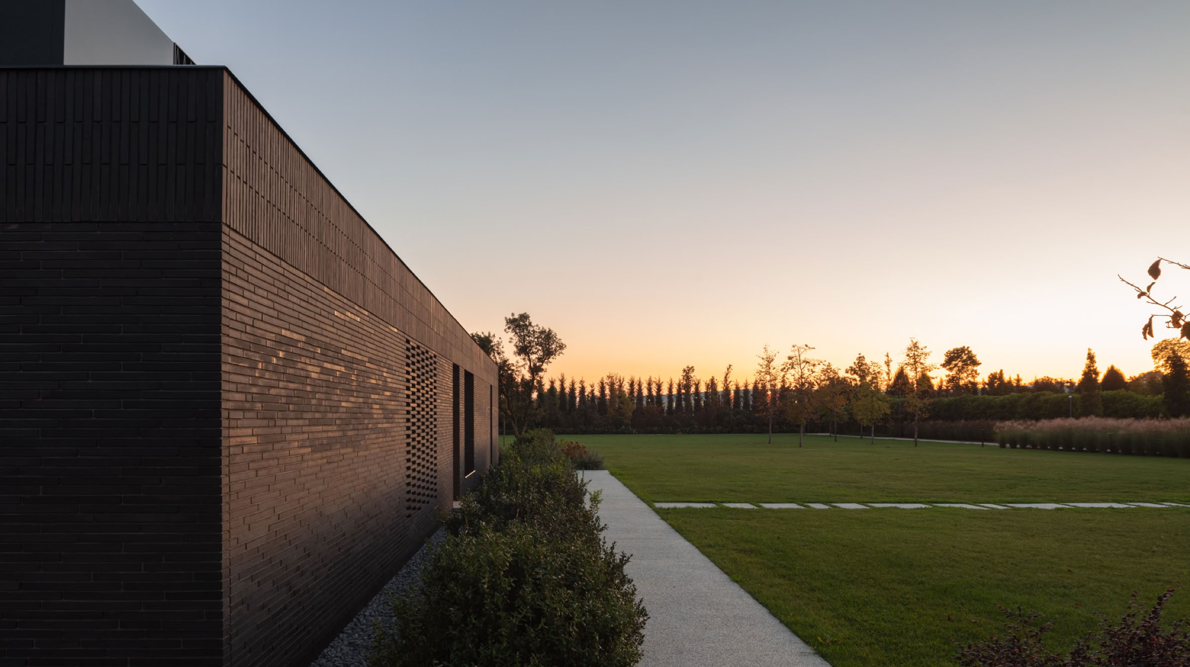 Esterni in mattoni al tramonto della villa nel parco progettata in Veneto da MIDE architetti. 