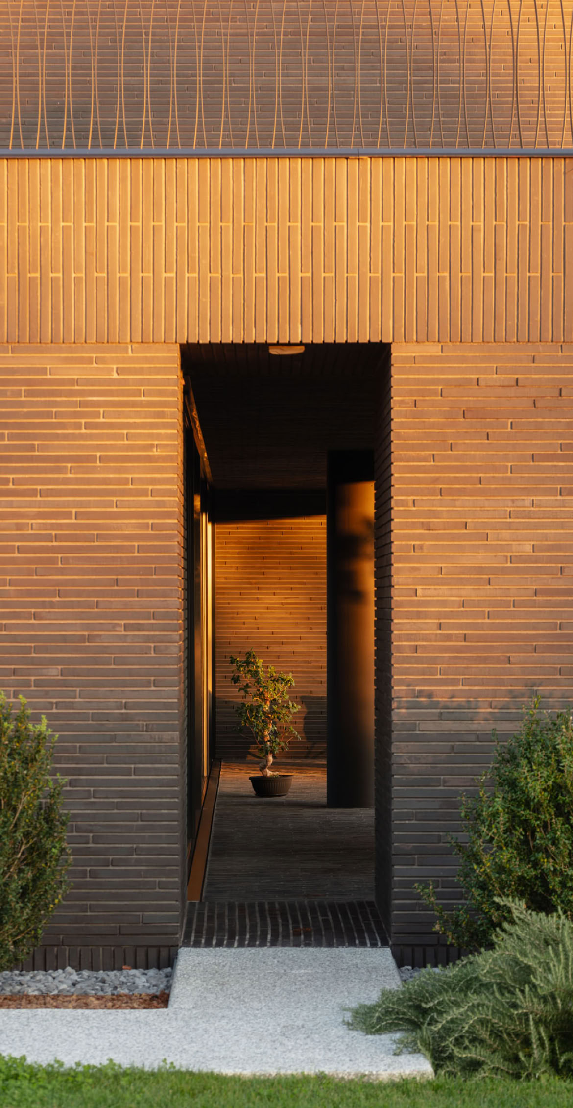 Dettaglio dell'accesso della villa in mattoni nel parco progettata da MIDE architetti.