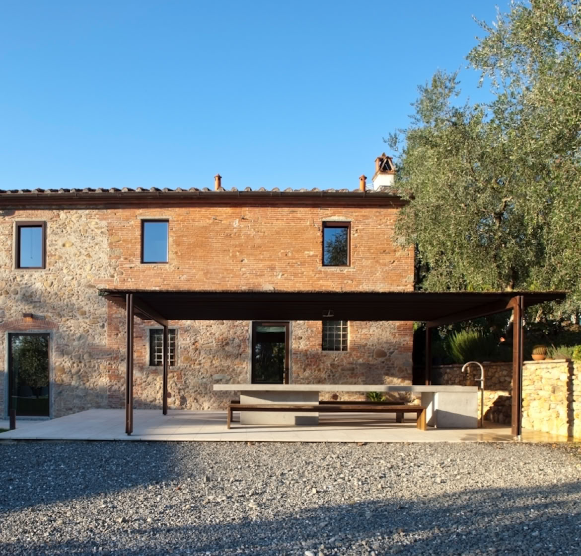 Zona ombreggiata con vista sul giardino, che mette in dialogo la tradizione rurale e il comfort contemporaneo.