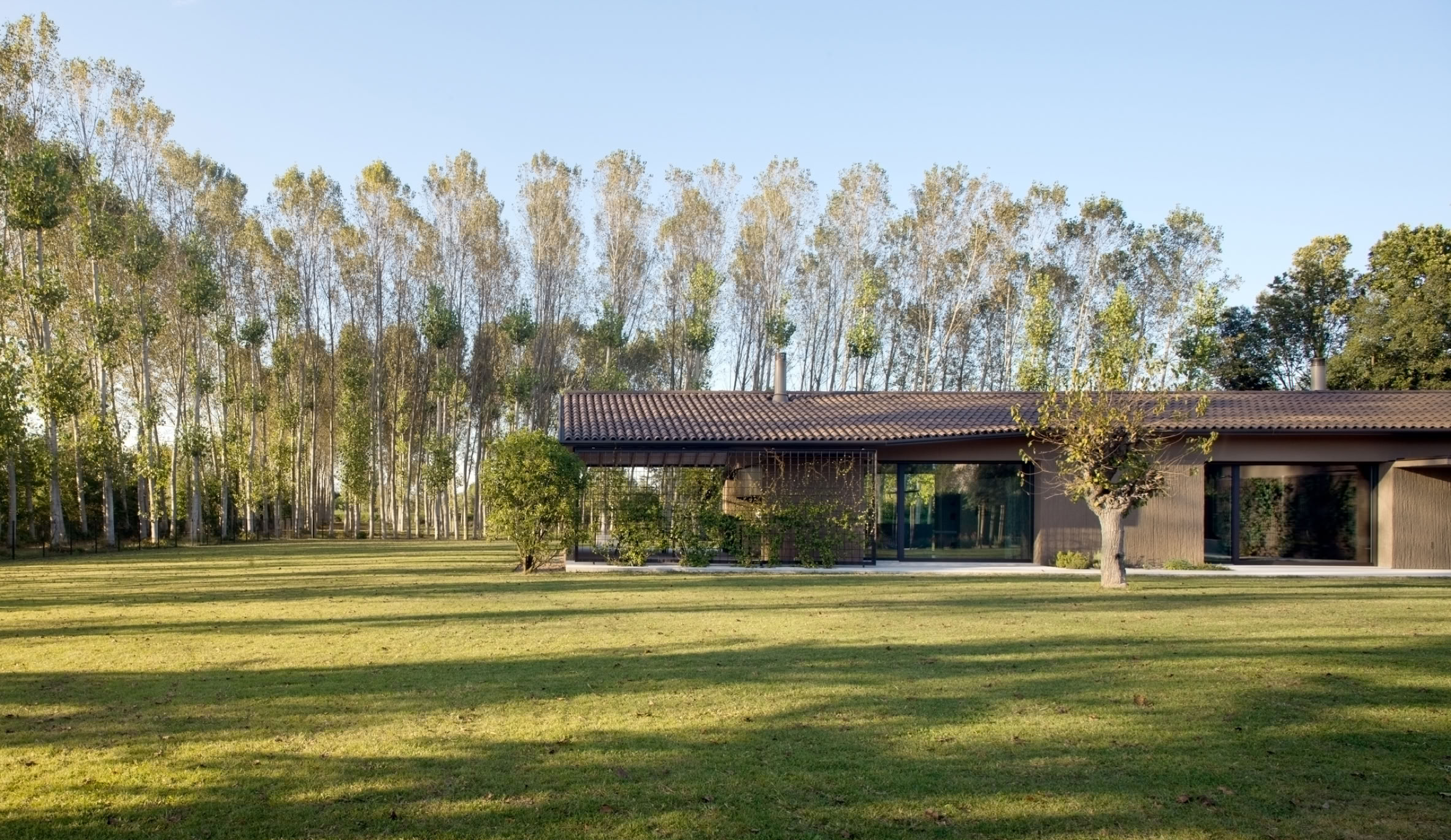 La villa si inserisce nel paesaggio della campagna veneta attraverso volumi essenziali, materiali materici e un dialogo continuo con la natura circostante.