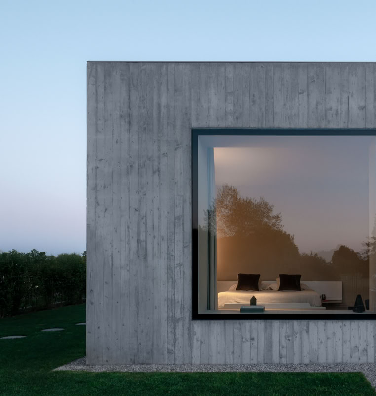 La matericità del calcestruzzo esposto definisce il carattere monolitico della villa, accentuando la semplicità formale e il forte legame con la luce naturale.